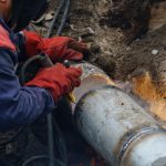 Close up of utility worker fixing broken water main. Sewerage pipe repair concept. Top view.