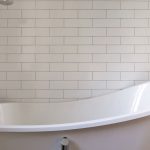 Empty bathtub in the bathroom on background of brick tiles