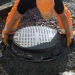 Installing cast iron sewer hatch on a concrete base of installation of water main sewer well in the