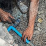 Plumber is hammering the PVC pipe installation in the renovated bathroom