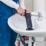 Professional plumber unclogging a sink